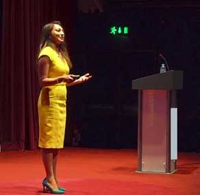 Shabnam Parkar wearing yellow dress on stage presenting at at TEDx